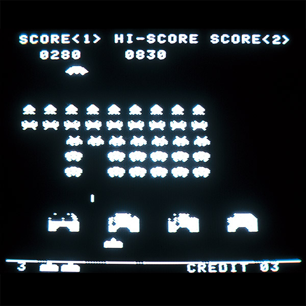 Original Space Invaders arcade playfield with a descending alien formation above shields and the player cannon